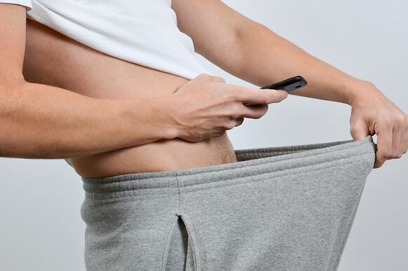 ένας άντρας κοιτάζει κάτω από το παντελόνι του ένα διευρυμένο πέος